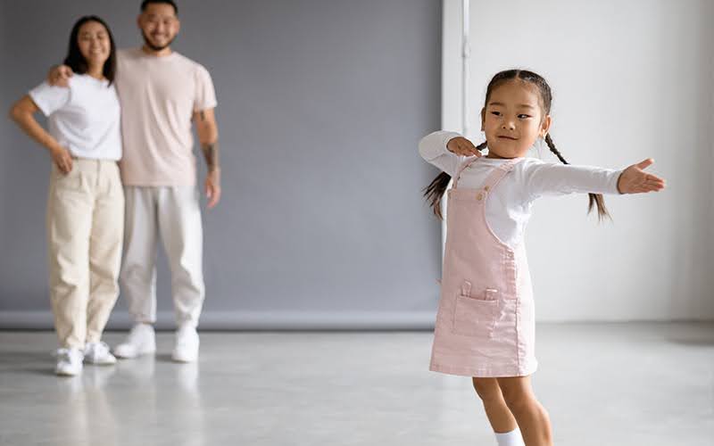 Child posing in a dance studio with parents.