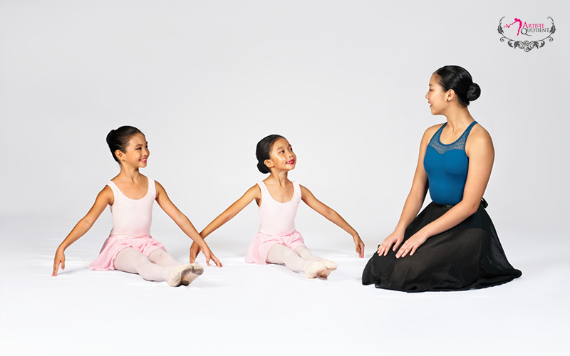 A teacher guiding young children in their first ballet class.
