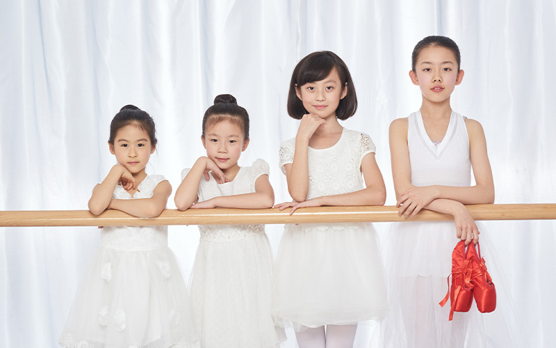 Four young ballet students posing at the barre.